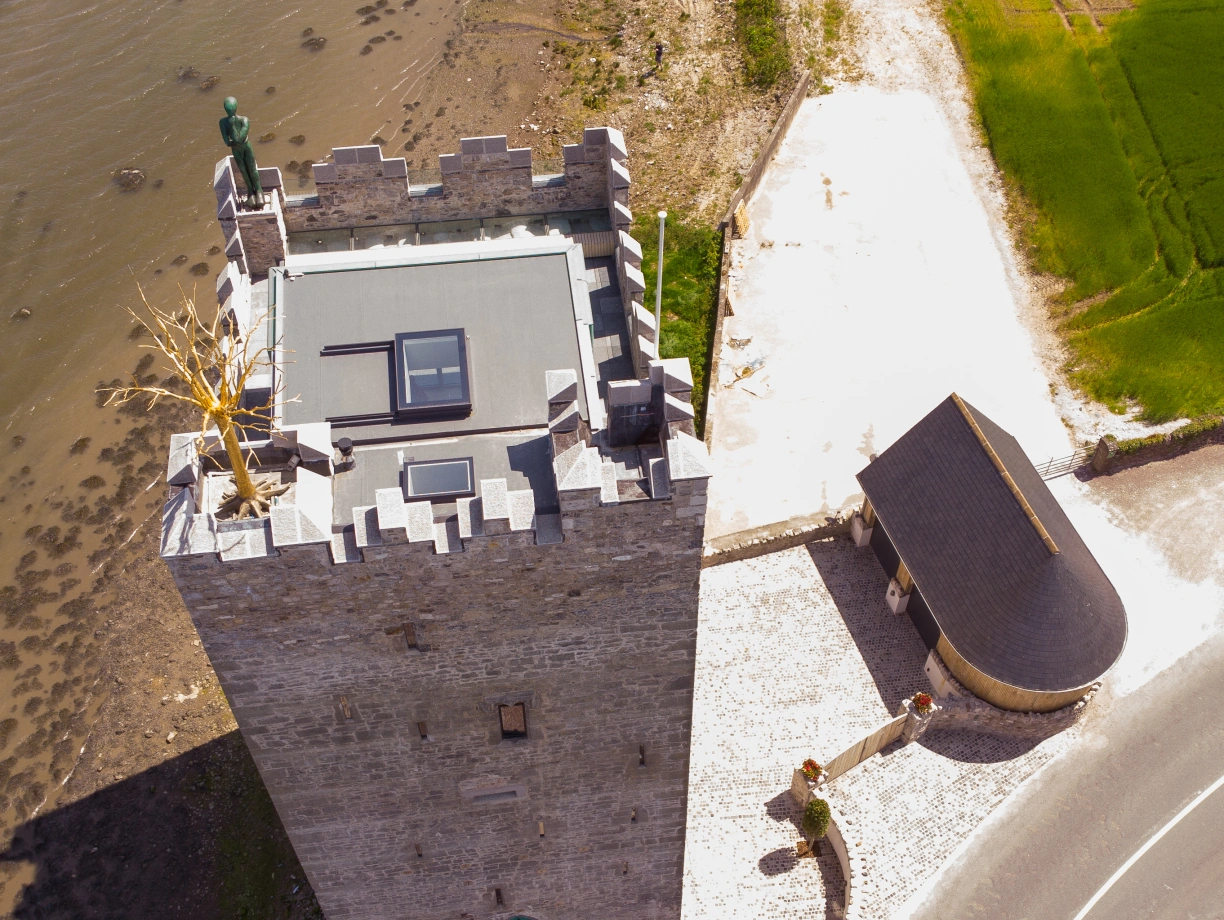 Un castel grando con un techo moderno, situat sur un riviera. La estrutura es circundata per paves e un parcare. Un sentiero conduce al entrata del castel.