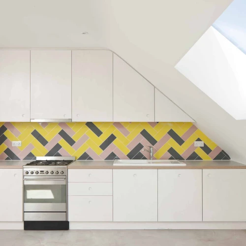 Modern kitchen featuring sleek white cabinetry, a stainless steel stove, and a colorful herringbone-patterned backsplash in shades of yellow, pink, and gray. A skylight adds natural light to the space.