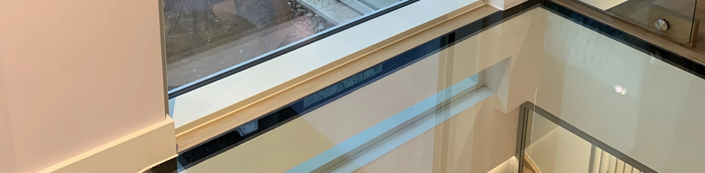 Großes Fenster zeigt die Außenseite eines modernen Hauses mit einem Spiegelbild der Person im Inneren. Der Boden ist aus Glas und gibt einen Blick auf die darunterliegende Ebene frei.