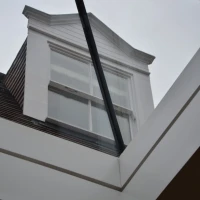 Vist de un tet frontal de casa, observat tra un vetro transparente. La nube es gris e la estructura es moderna.