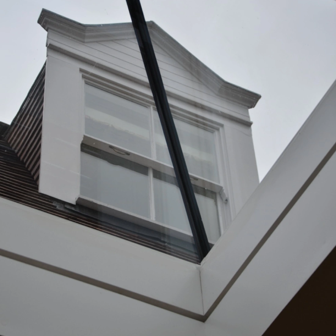 Vist de un tet frontal de casa, observat tra un vetro transparente. La nube es gris e la estructura es moderna.