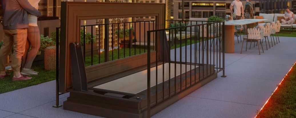 A rooftop gathering at dusk features people enjoying the scenic city skyline. Some are taking selfies, while others are seated at tables with lights strung above. A fire pit is visible, surrounded by greenery, adding to the cozy atmosphere.