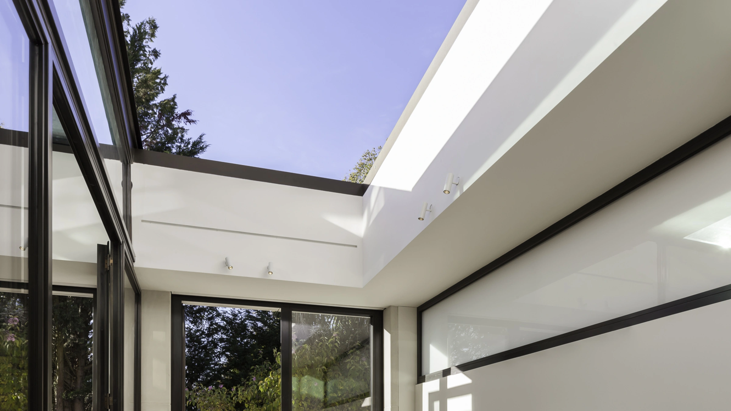 Sala de comedor moderna con una mesa de madera, sillas de diseño acogedor y grandes ventanales que permiten la entrada de luz natural. La decoración es minimalista y hay vistas al jardín exterior.