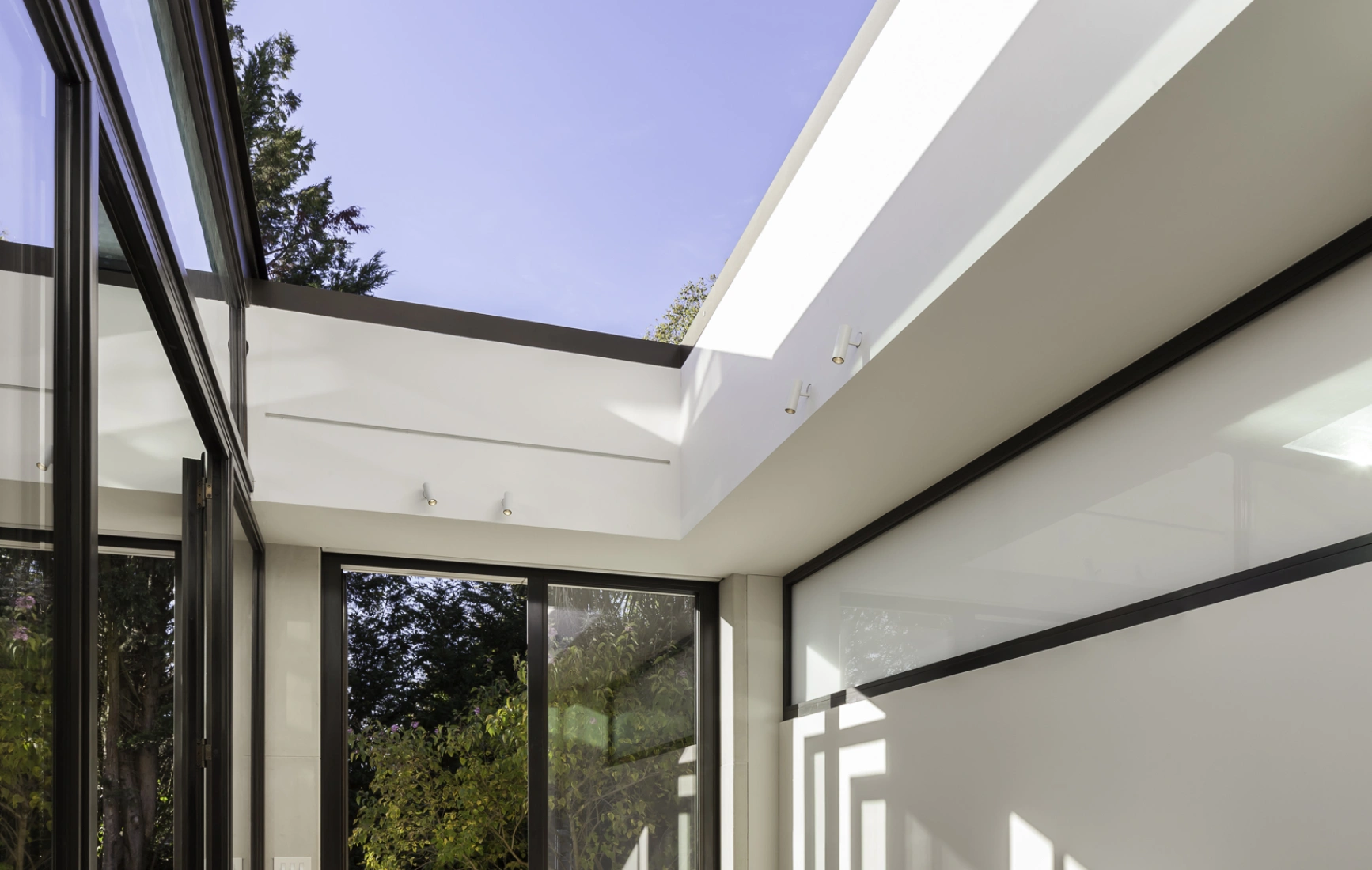 Sala de comedor moderna con una mesa de madera, sillas de diseño acogedor y grandes ventanales que permiten la entrada de luz natural. La decoración es minimalista y hay vistas al jardín exterior.